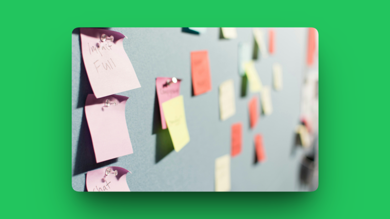 A bulletin board covered with rows of colorful sticky notes pinned across its surface.
