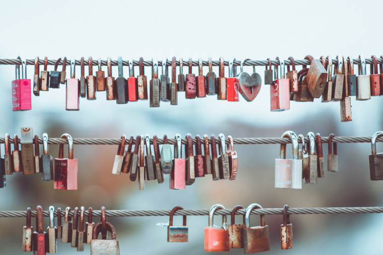 Padlocks of various sizes clustered on cable wires.