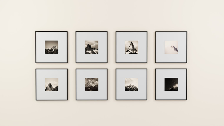 Eight black-and-white mountain photographs in matching frames arranged in a gallery wall grid