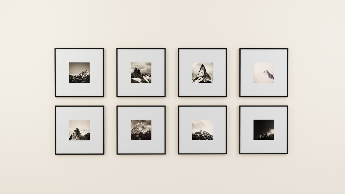 Eight black-and-white mountain photographs in matching frames arranged in a gallery wall grid
