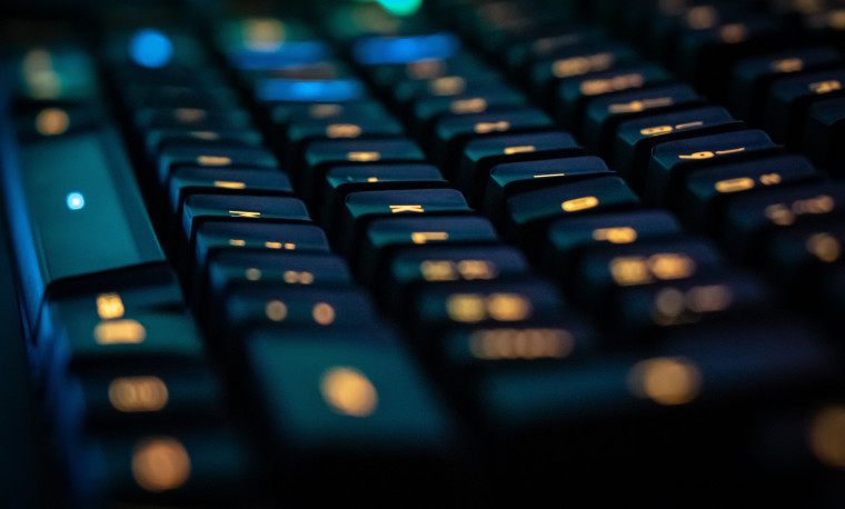 A close-up photo of a backlit mechanical keyboard with illuminated keys.