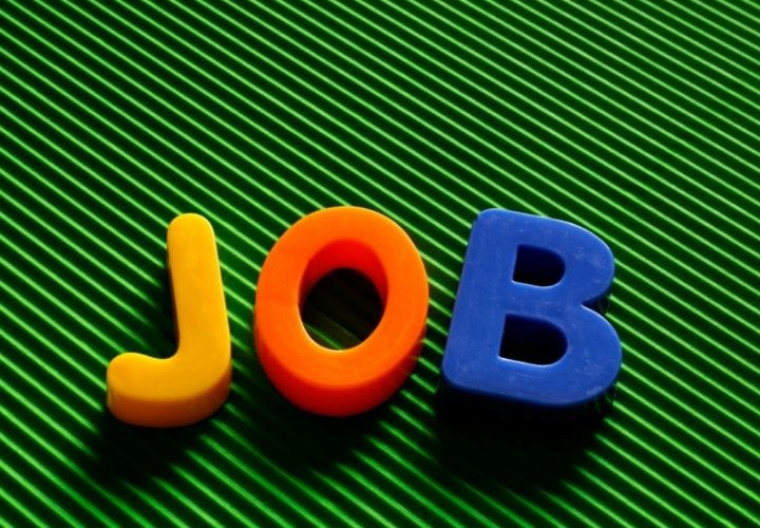 Colorful toy letter tiles spelling 'JOB' on a green ribbed surface.