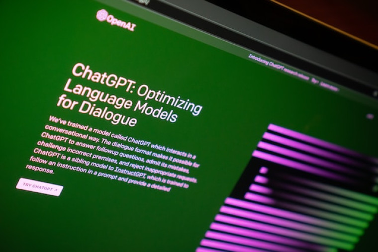 A photo of the OpenAI website's ChatGPT announcement page, headlined 'ChatGPT: Optimizing Language Models for Dialogue' on a green background.
