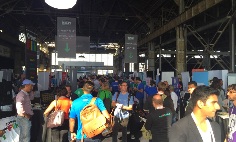 The TechCrunch Disrupt conference floor showing Startup Alley sections packed with attendees and exhibitor booths.