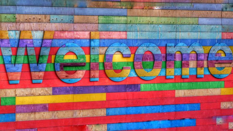 A colorful striped wooden wall with large 3D letters spelling 'Welcome'.