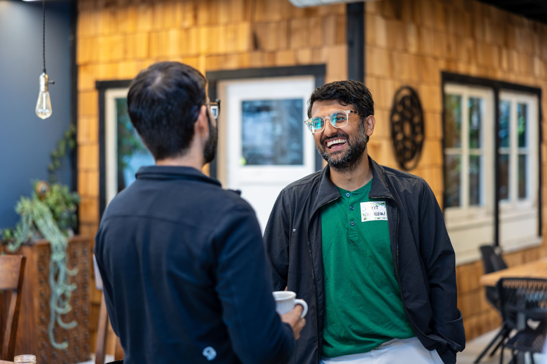 Two people in casual conversation at a Chameleon IRL event, one wearing a Chameleon name badge
