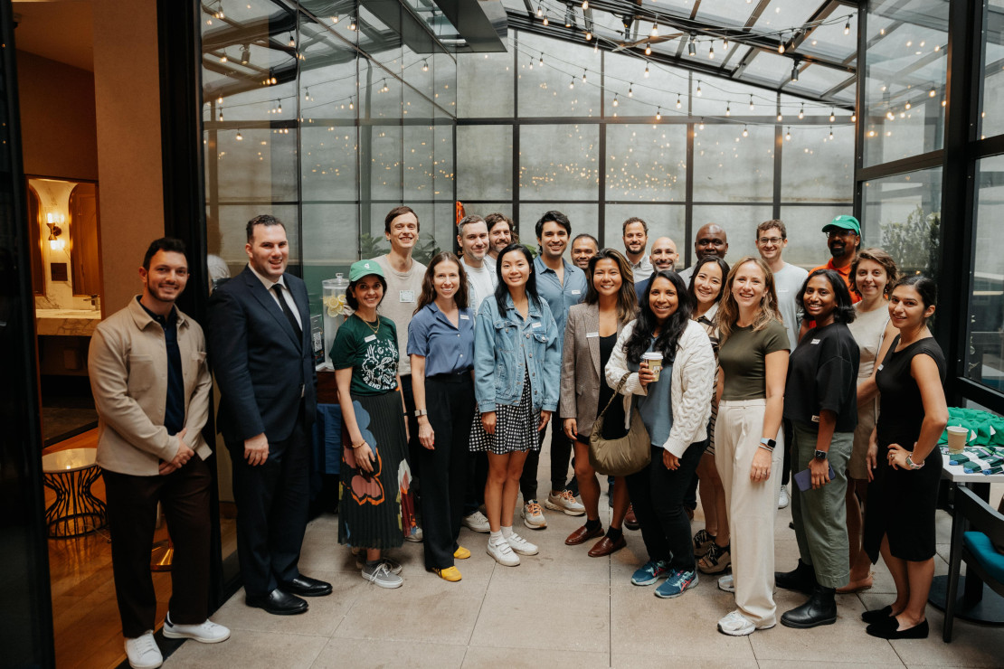 A group of attendees gathered for a Chameleon product event in New York, posing together in a glass-roofed venue with string lights.