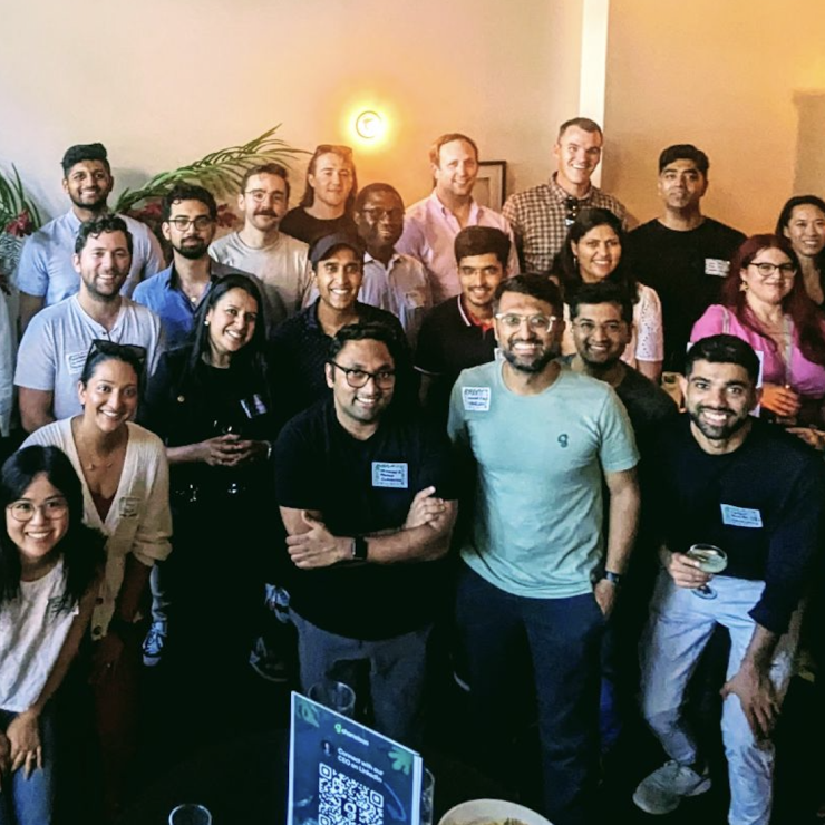 Attendees gathered at a Chameleon in-person networking event, posing together in a warmly lit indoor venue