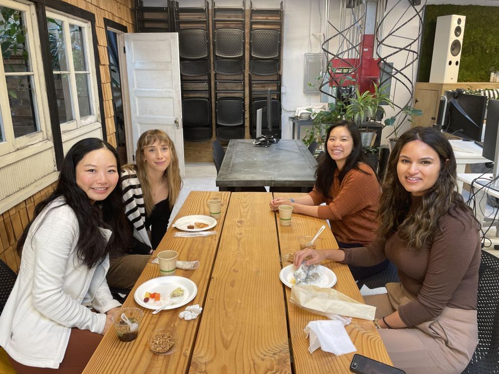 Four attendees seated at a wooden table sharing a meal at a Chameleon in-person event.