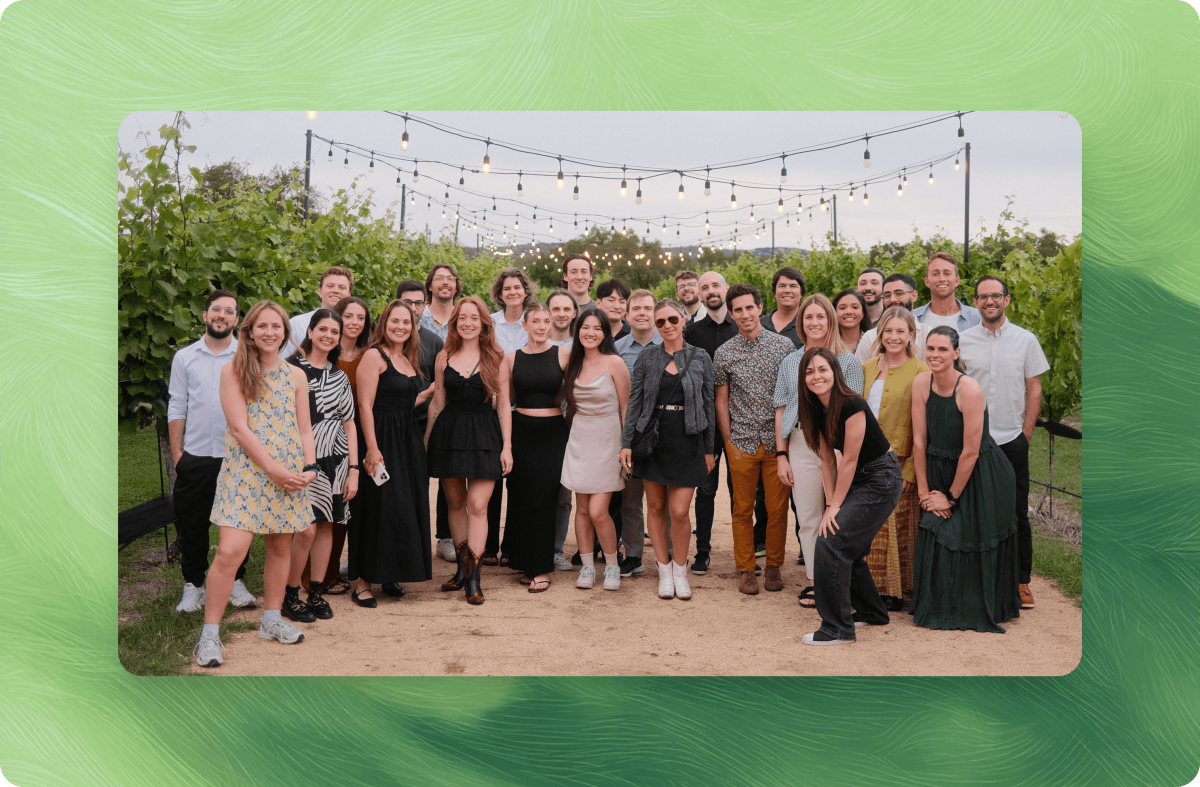 The Chameleon team gathered outdoors at an evening company event, with string lights overhead in a vineyard setting.