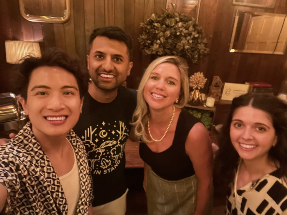 Four people smiling together for a selfie at an indoor event venue.
